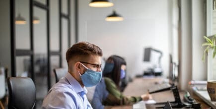 man and woman sitting at desk with masks on in the workplace