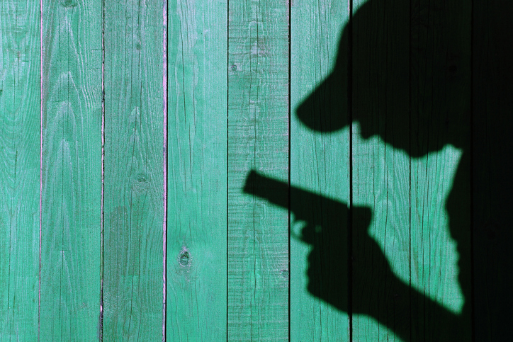 Shadows of a Men with a handgun on a natural grunge wood background, with space for text or image. You can see more on my page.