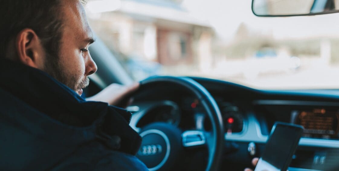 Man looking at cellphone while behind the wheel