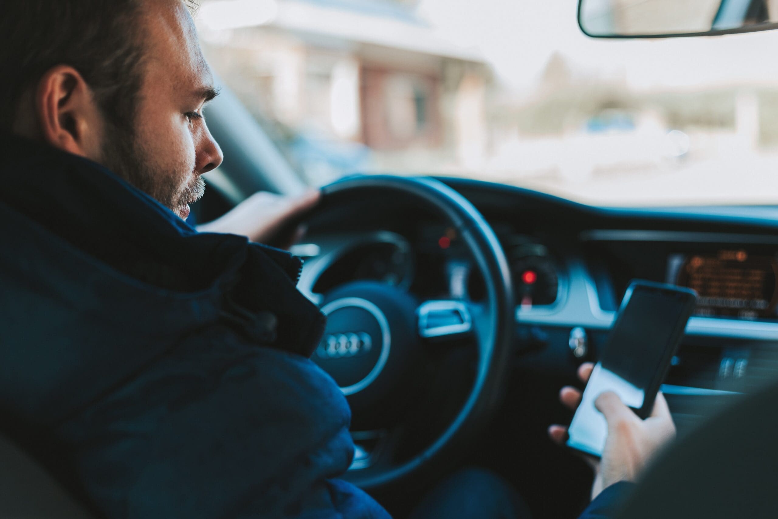 Man looking at cellphone while behind the wheel