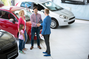 car salesman showing new vehicle to family customers
