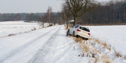 white suv crashed in a country road kerbside due to slippery road covered in snow with skid marks
