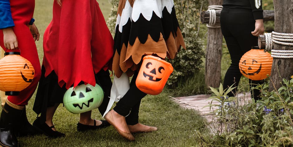 Kids in costumes carrying Halloween buckets for candy