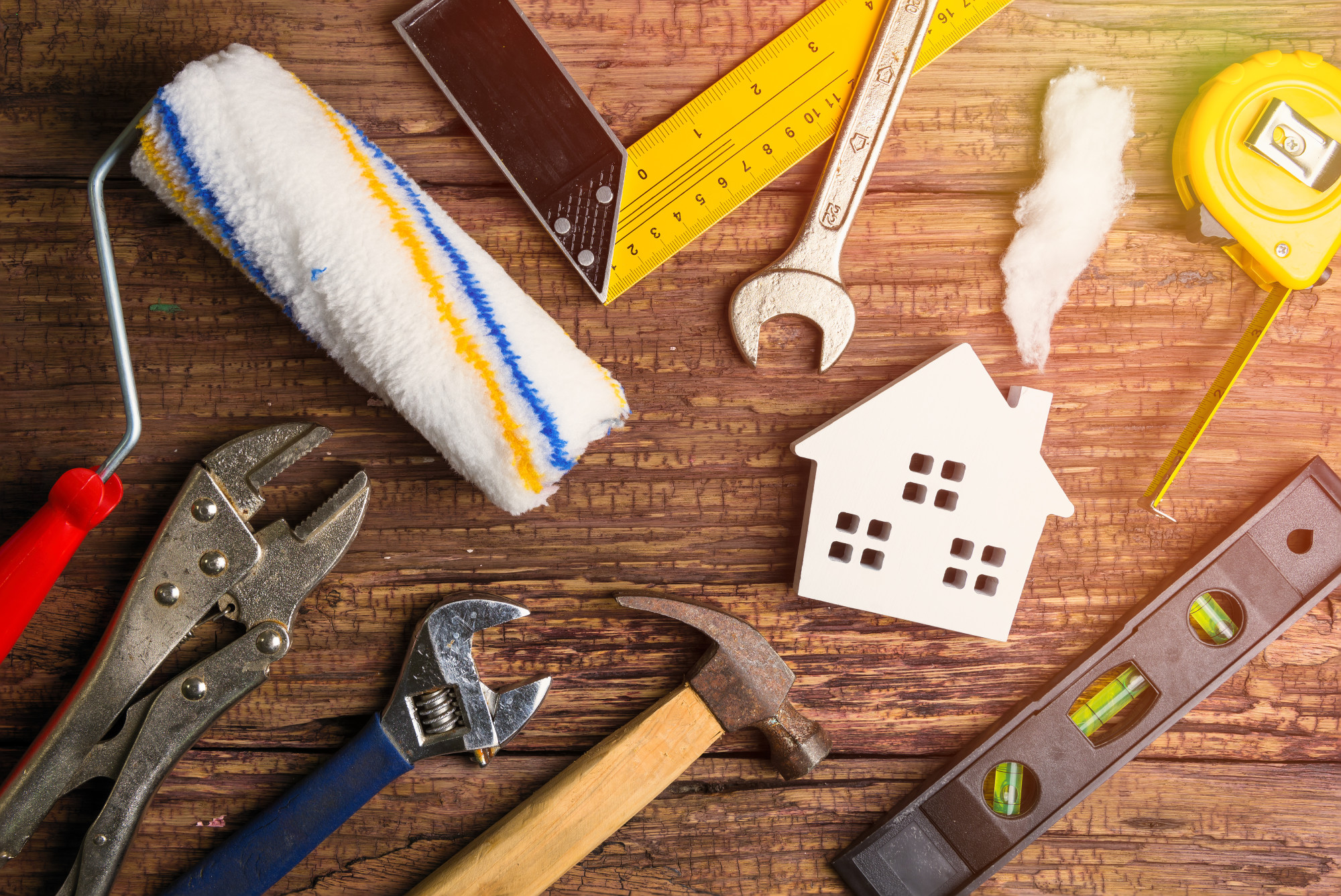 Mini white house laying on table surrounded by tools for home maintenance concept