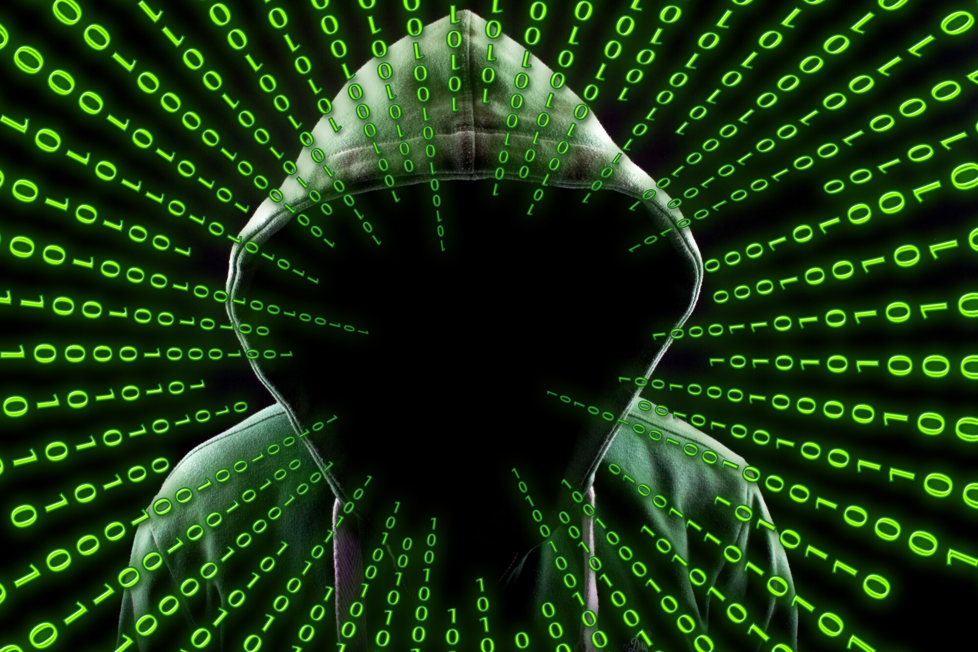 hidden person in green and black hoodie symbolizing cyber attacks