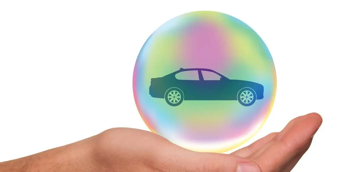 Hand holding car in a bubble