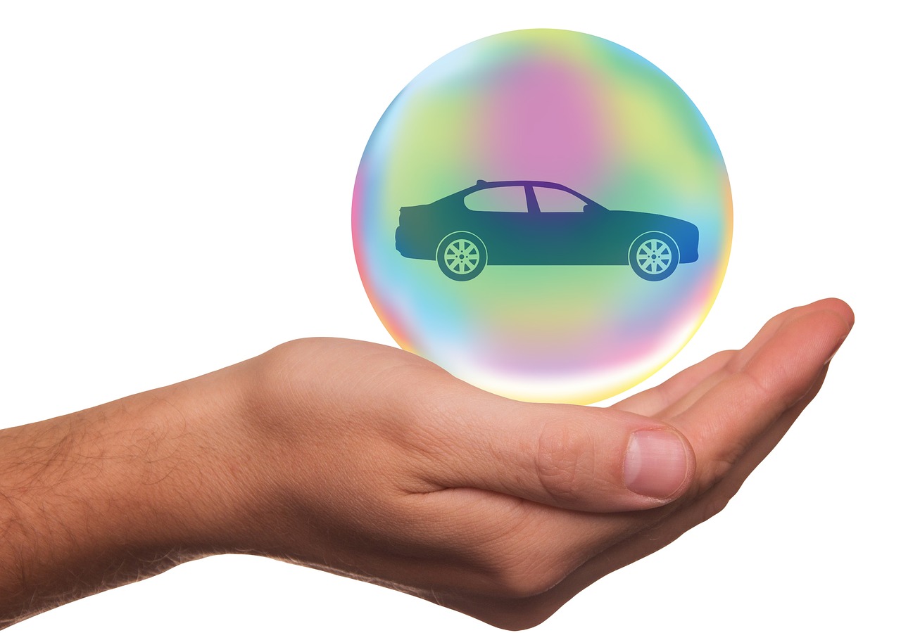 Hand holding car in a bubble