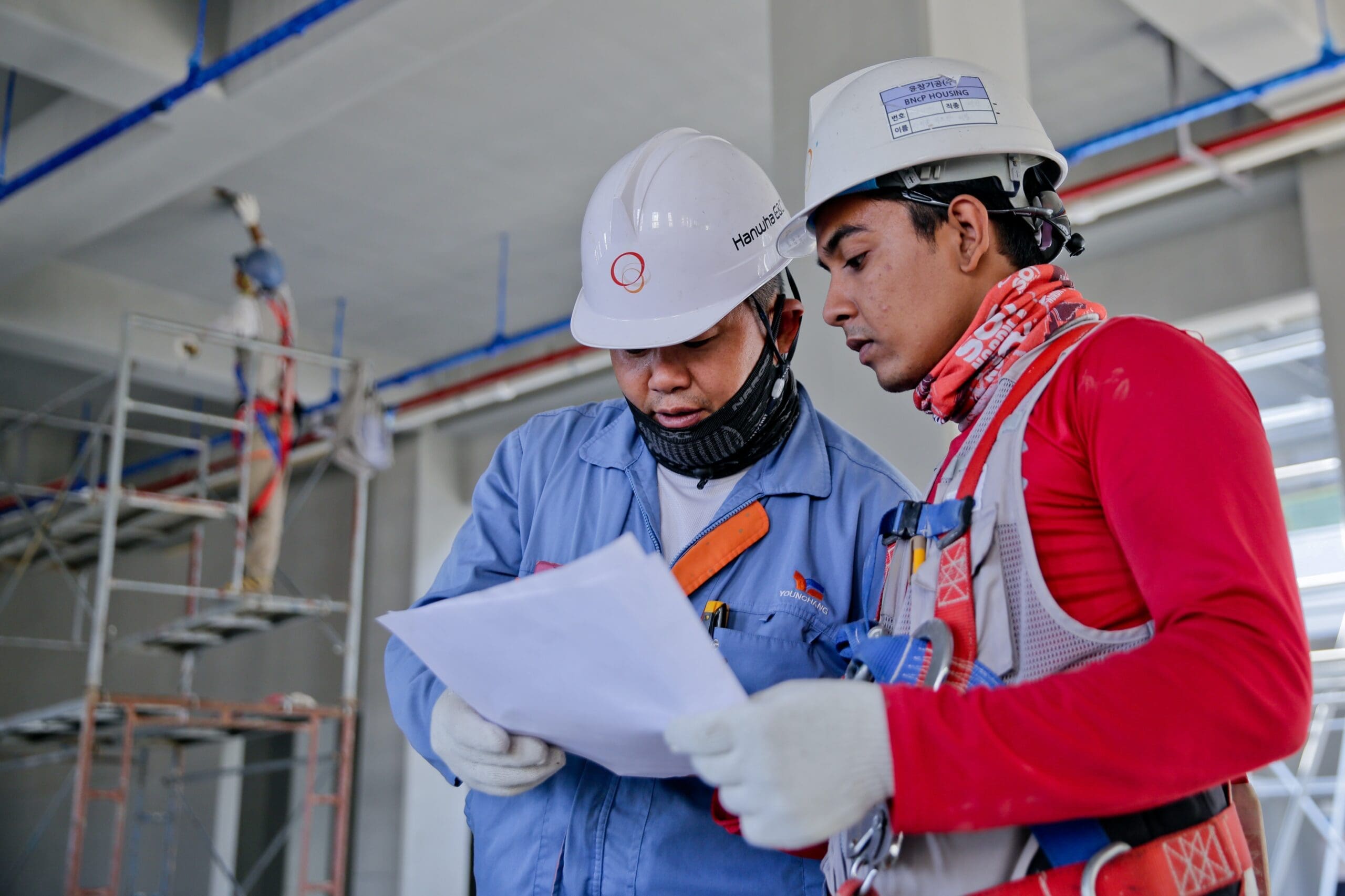Two people wearing hard hats are reading an article about the top 5 OSHA violations of 2021  to better prepare for their future working endeavors.