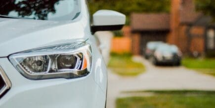 closeup of white car in driveway for auto reform concept