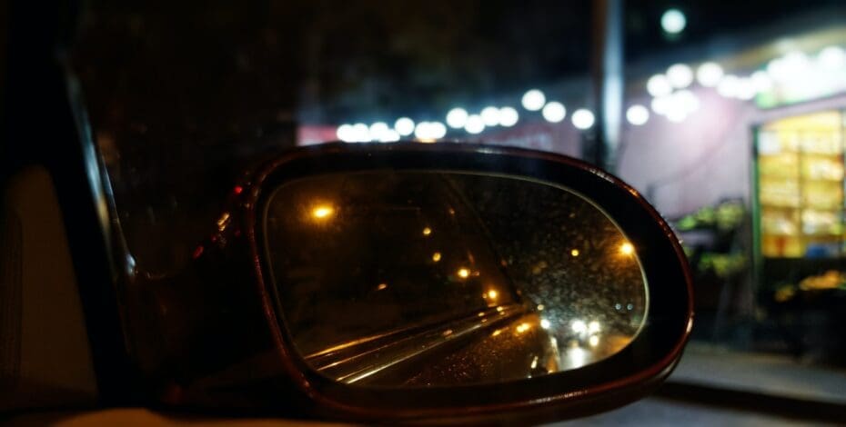 side mirror of car adjusted to view traffic at night