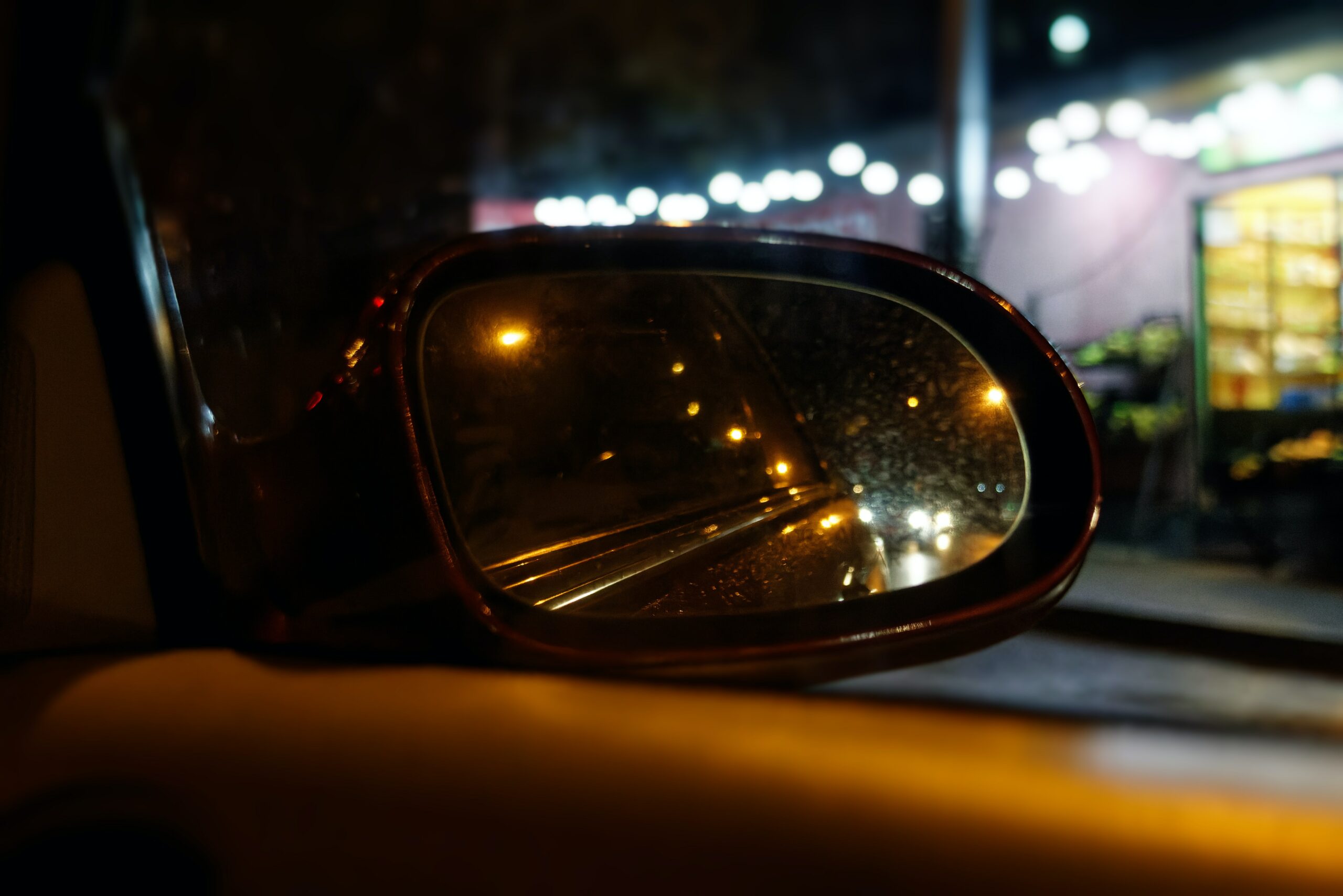 side mirror of car adjusted to view traffic at night
