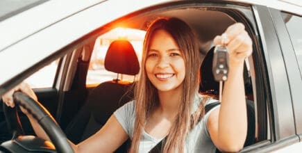 Young happy woman showing the key of new car