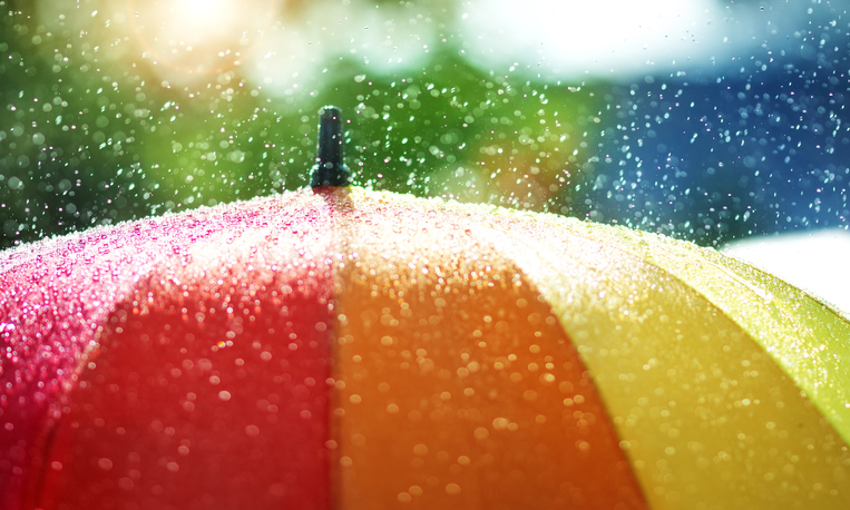 Rain drops falling onto umbella with rainbow colour- Rainy weather