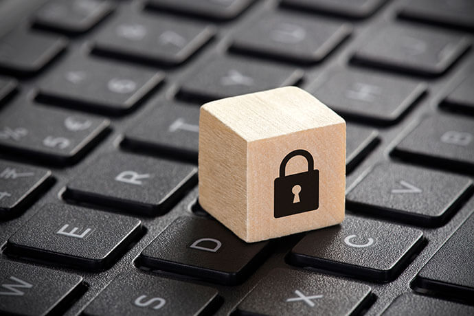 Wooden block with lock graphic on laptop keyboard. Computer security concept.