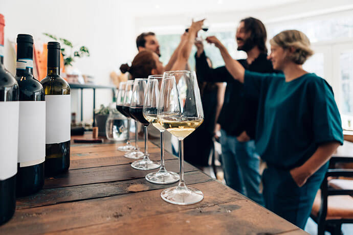 people inside a bar chilling out with a drink - friends talking and drinking in a winery - Millennials toasting at a wine tasting