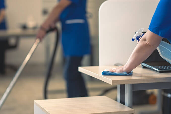 Cleaning an office table.Other cleaners clean in the background