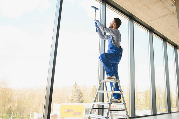 Young man cleaning window in office