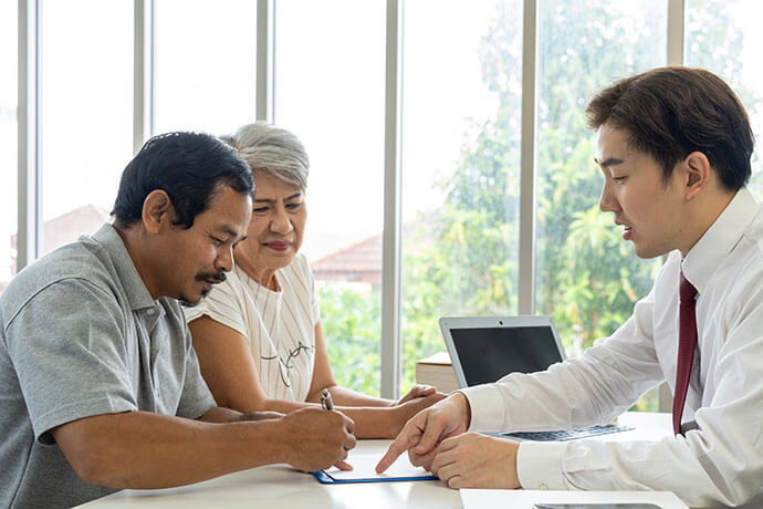 Asian young employee is offering about life insurance plan to aged couple