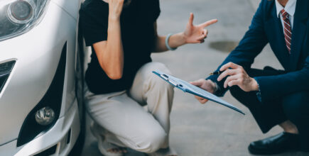 Someone was just in a car accident and an insurance agent is assessing the damage to the car.