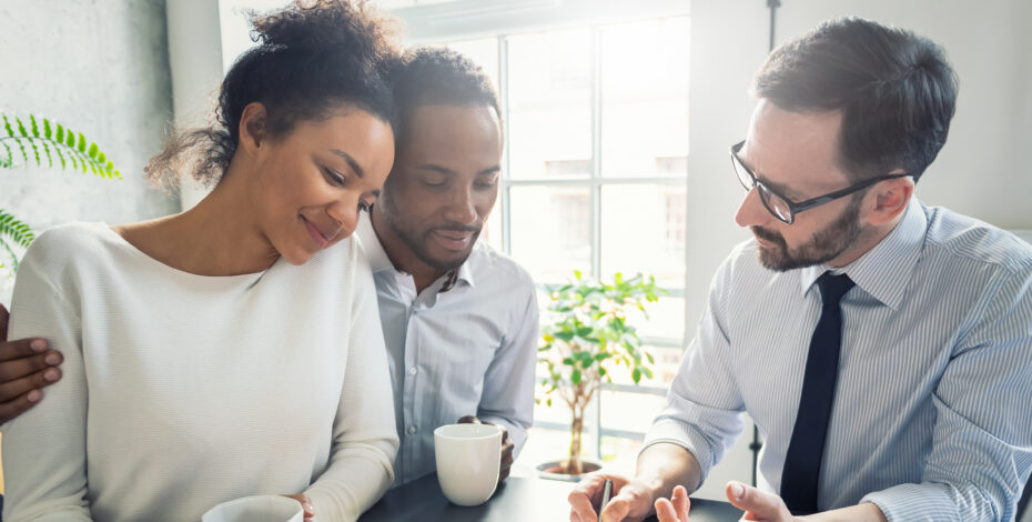 An insurance agent assisting a couple with getting insurance.